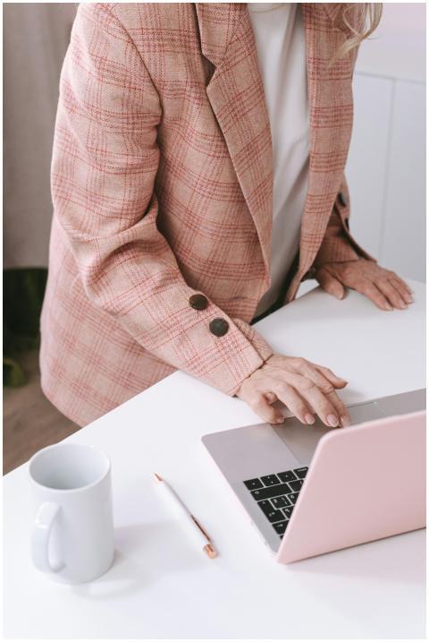 Businesswoman in a pink plaid suit using a laptop