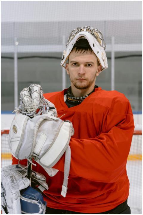 Focused ice hockey goalie in gear on indoor rink,