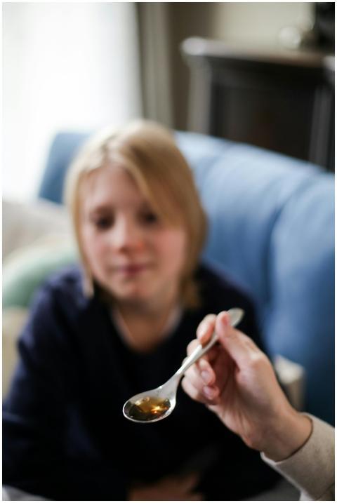 Out of focus child ready to take liquid medicine f