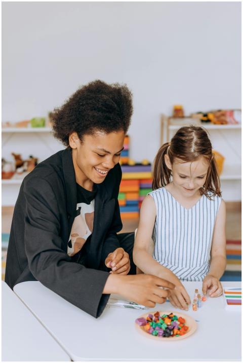 Smiling teacher assists a young girl with a colorf