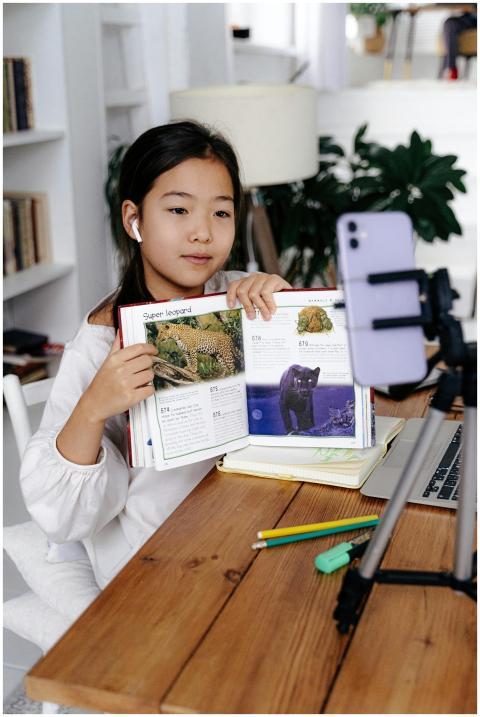 Young girl displays book during online class using
