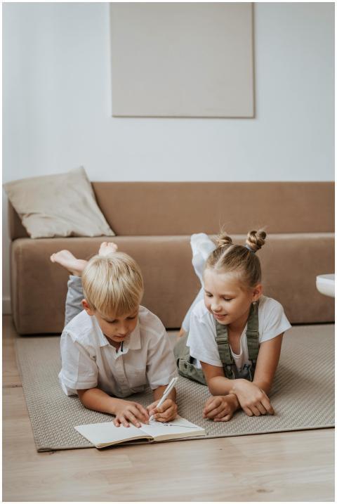 Siblings lying on the floor, doing homework togeth