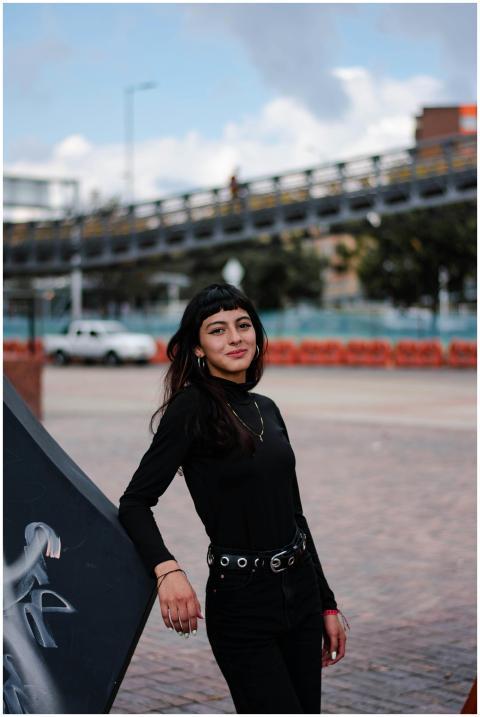 Confident woman in black outfit posing outdoors wi