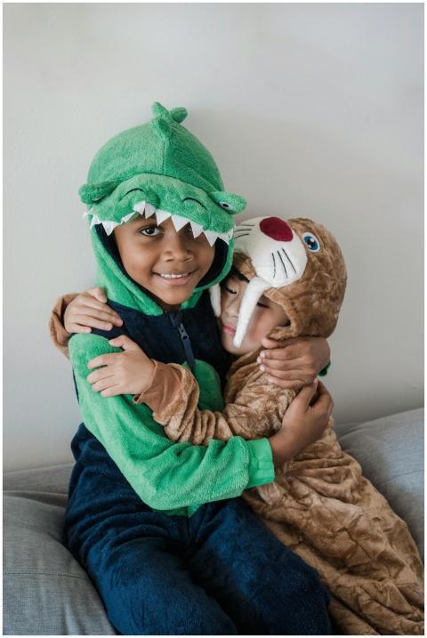 Two children in cute animal onesies sharing a lovi