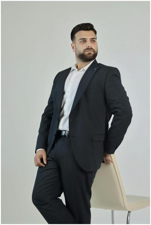Confident man in a formal suit posing indoors, exu