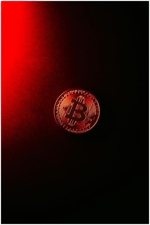 Close-up of a Bitcoin coin illuminated by red ligh