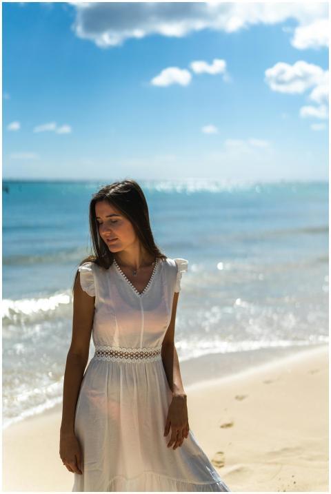 A woman in a white dress enjoys the sun on a beaut