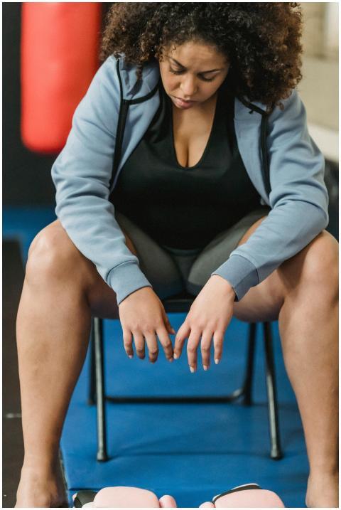 A woman in activewear sits on a chair in the gym,