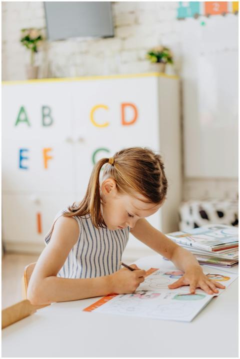 A young girl focused on coloring a book in a prima