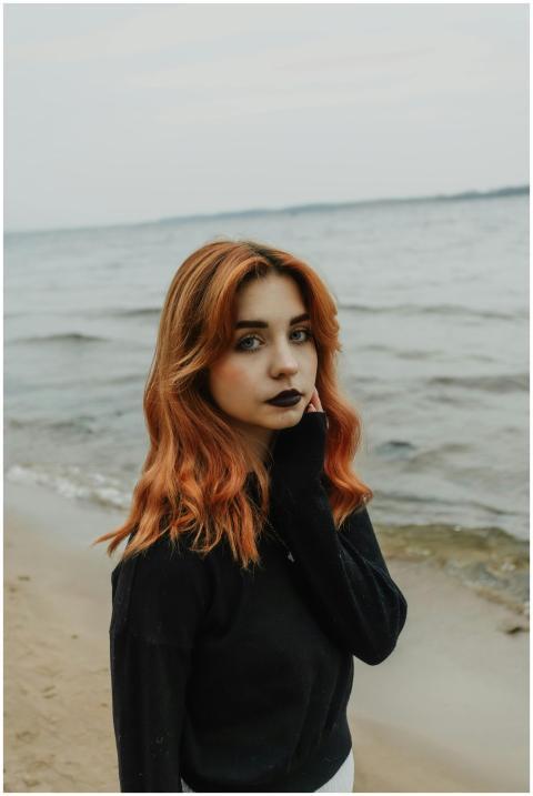 Portrait of a young woman with red hair standing b