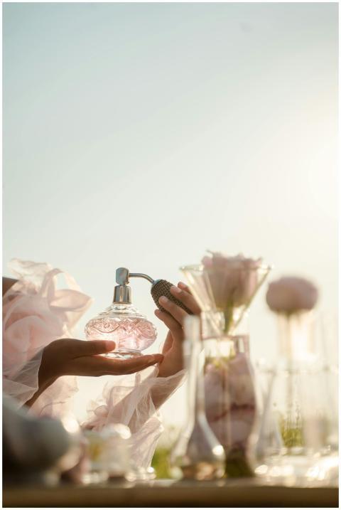 A delicate perfume bottle is held with a floral ar