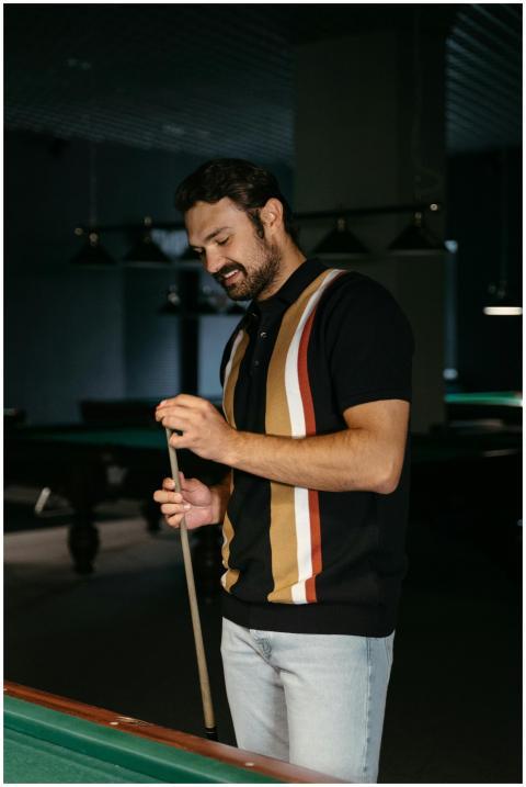 A man holds a cue stick while playing pool in a st
