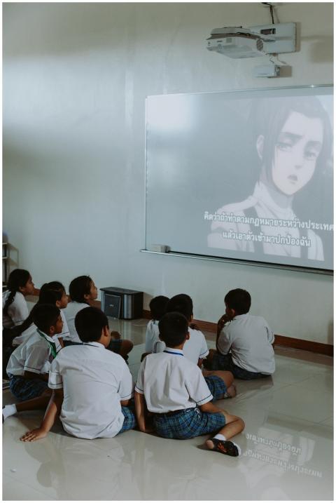 Group of school children watching anime on a proje