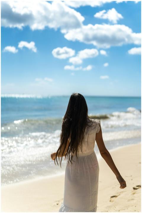 A woman in a white dress strolls along the beautif