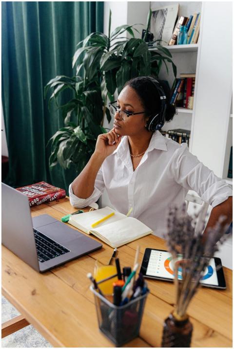 A woman in a white shirt using a laptop and tablet