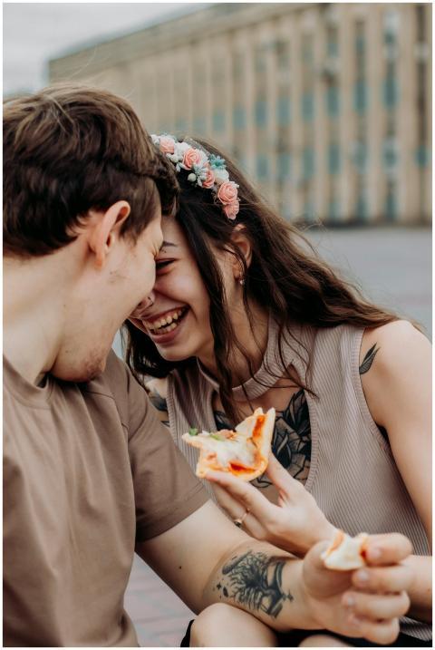 Smiling couple sharing a pizza and laughter outdoo