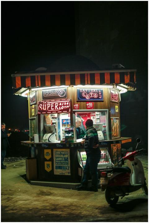 Illuminated urban scene of a newsstand at night wi