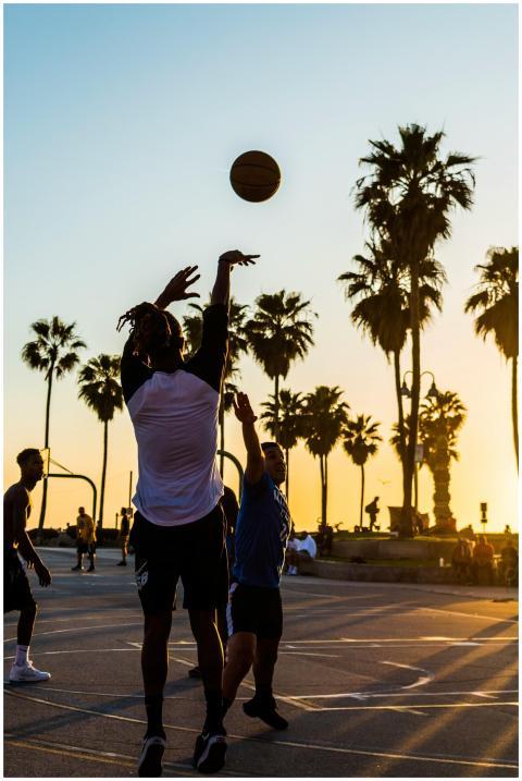 Players enjoy a casual basketball game under palm