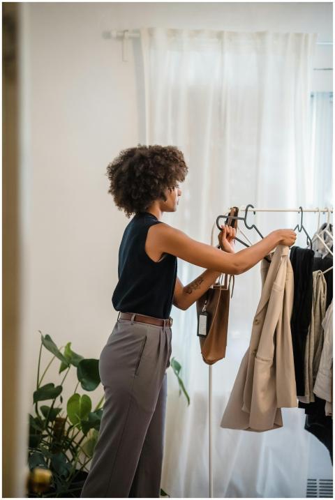 A stylish woman arranges clothes in a room with lu