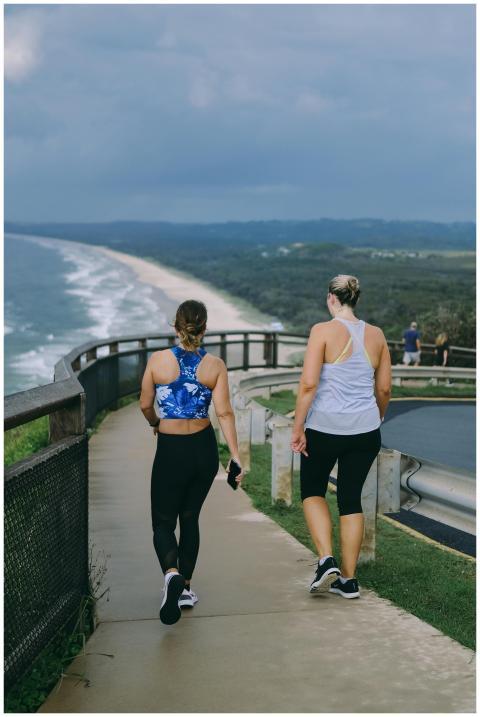 Two women walking on a coastal path with ocean vie