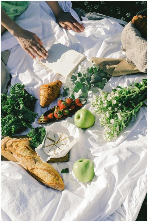 A picnic setup with fresh fruits, vegetables, brea