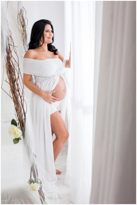 A pregnant woman smiles while looking out the wind
