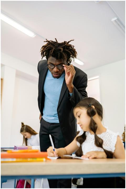 Teacher assisting young student with learning in a