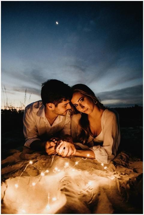 A couple lying on the beach at twilight, illuminat