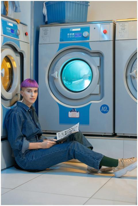 Stylish young woman with dyed hair sitting by wash