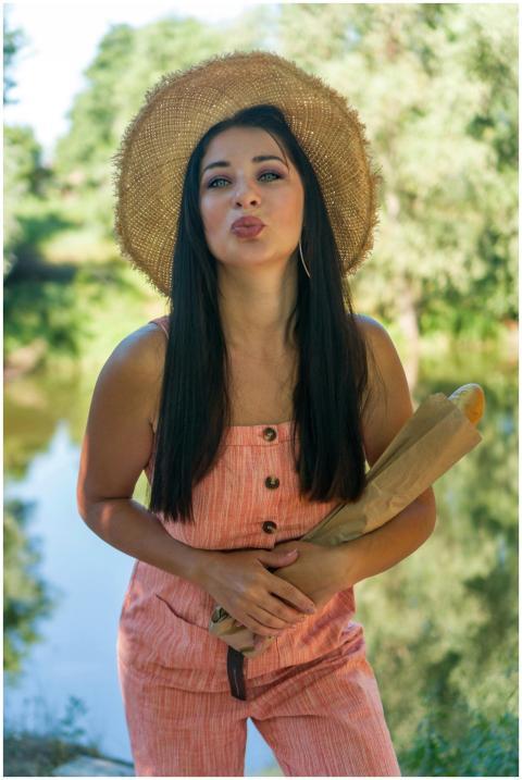 Young woman in a summer outfit holding a baguette,