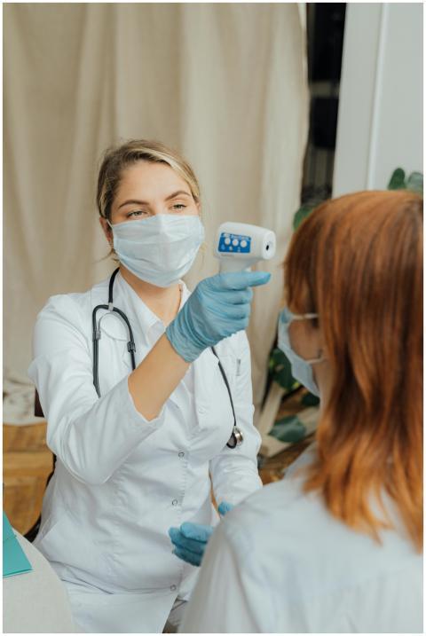 A female doctor uses a thermometer to measure a pa