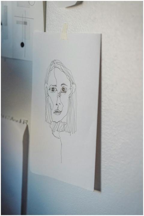 Simple pencil sketch of a face taped on a wall, sh