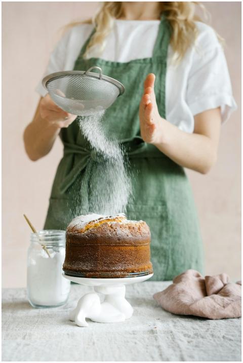 Woman decorating a homemade cake with powdered sug