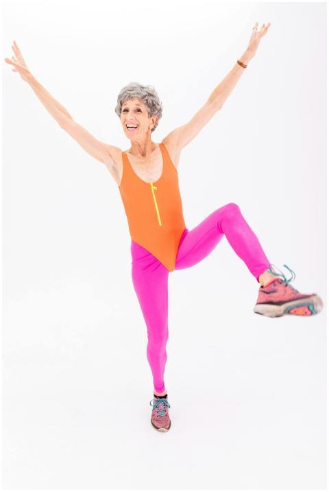 A senior woman in bright activewear demonstrates f