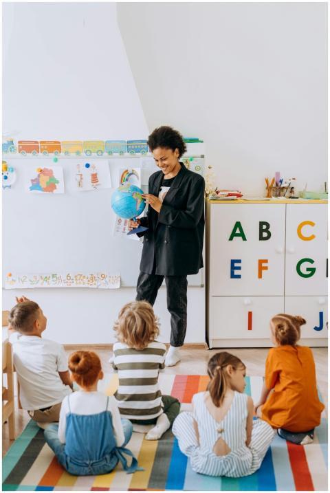 A teacher engaging preschool children with a globe