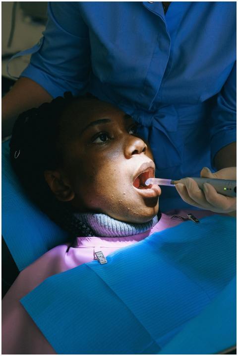 A woman undergoing dental treatment with curing li
