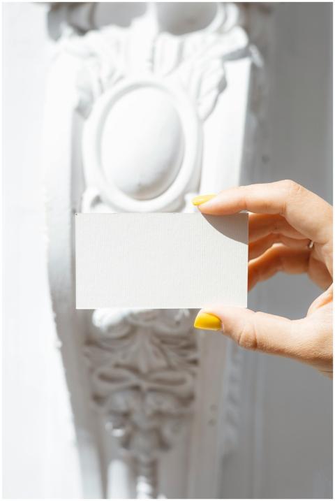 A woman's hand with yellow nails holds a blank car