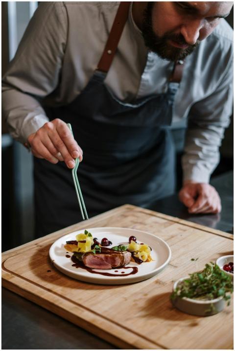 Chef artistically plating a gourmet dish with prec