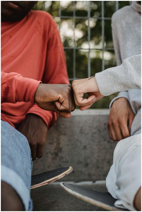 Close-up of diverse friends fist bumping while sit