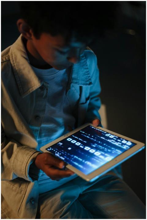 A child engrossed in using a digital tablet at nig