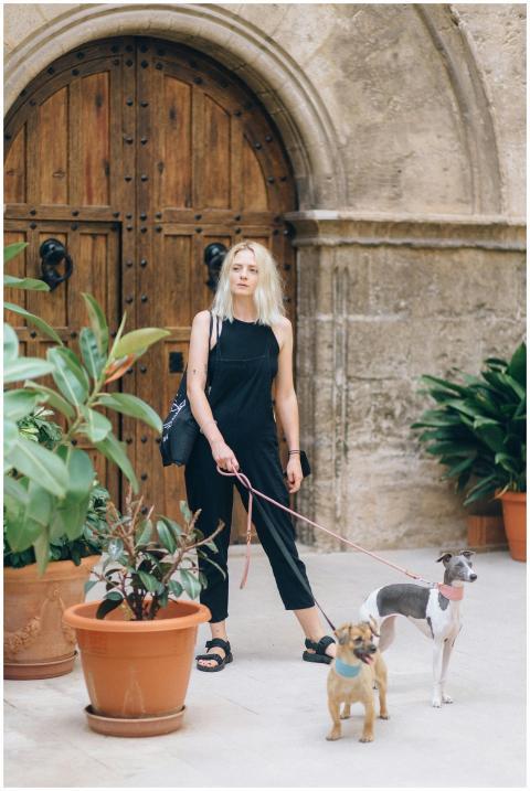 Blonde woman walks two dogs among potted plants ne