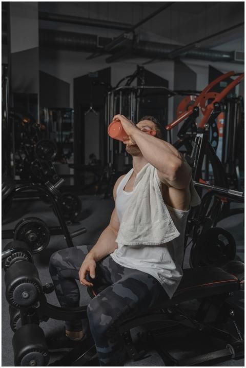 A muscular man with a towel rests and drinks water