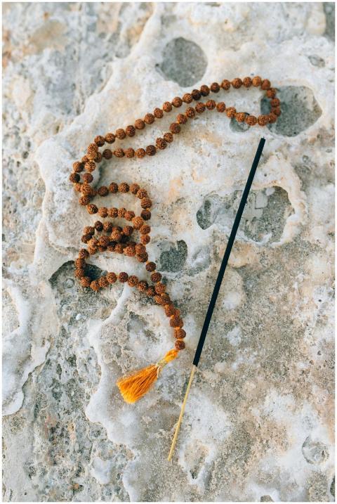 Prayer beads and incense stick on a natural stone
