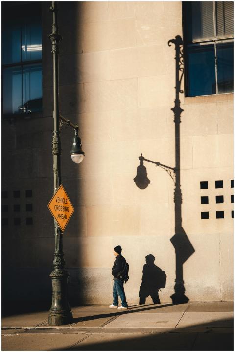 A person walks under dramatic shadows in a New Yor