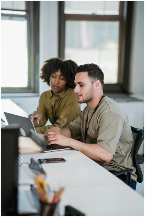 Two colleagues working together on a laptop in a m