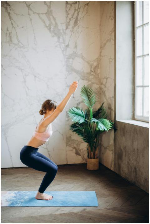 Adult woman performing yoga indoors with window li