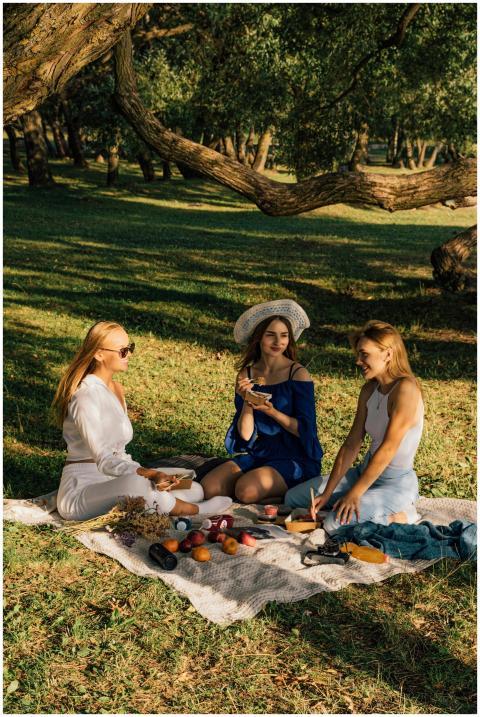 Three women enjoying a picnic outdoors in a sunny