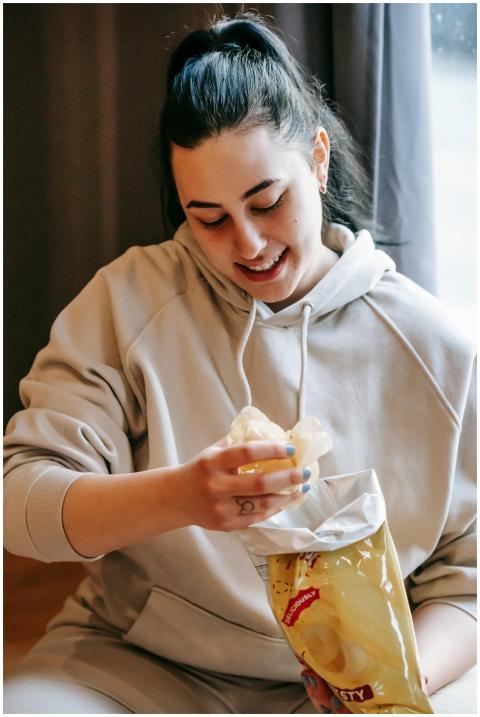 Smiling plump female wearing comfy hoodie eating c