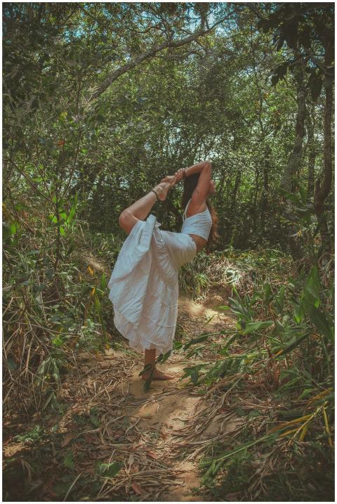 A woman in a white dress performs a yoga pose surr
