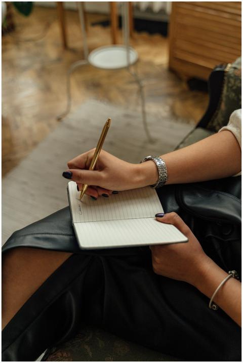 Close-up of hands writing in a notebook with a pen